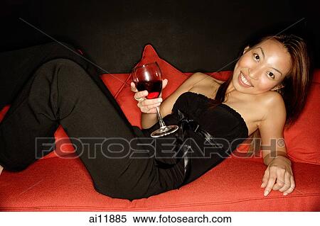 Woman holding wine glass leaning on sofa View Large Photo Image Stock Photography - Woman holding wine glass leaning on sofa. Fotosearch