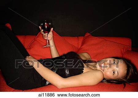 Woman holding wine glass lying on sofa, looking at camera View Large Photo Image Stock Photograph - Woman holding wine glass lying on sofa, looking at camera. Fotosearch
