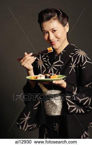 Woman in Japanese costume, holding chopsticks and eating sushi View Large Photo Image Stock Image - Woman in Japanese costume, holding chopsticks and eating sushi. Fotosearch