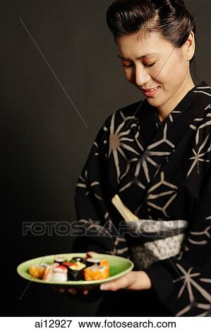 Woman in Japanese costume, holding plate of Japanese food View Large Photo Image Stock Photo - Woman in Japanese costume, holding plate of Japanese food. Fotosearch