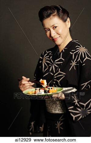 Woman in Japanese costume, holding chopsticks and a plate of Japanese food View Large Photo Image Stock Photo - Woman in Japanese costume, holding chopsticks and a plate of Japanese food. Fotosearch