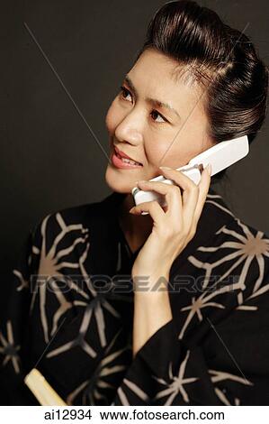 Woman in Japanese costume, using mobile phone, looking away View Large Photo Image Picture - Woman in Japanese costume, using mobile phone, looking away. Fotosearch