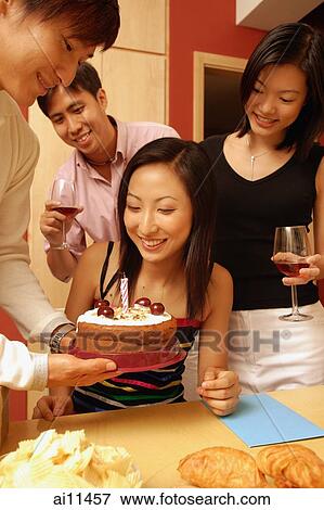 Woman looking at cake, surrounded by friends View Large Photo Image Stock Photo - Woman looking at cake, surrounded by friends. Fotosearch
