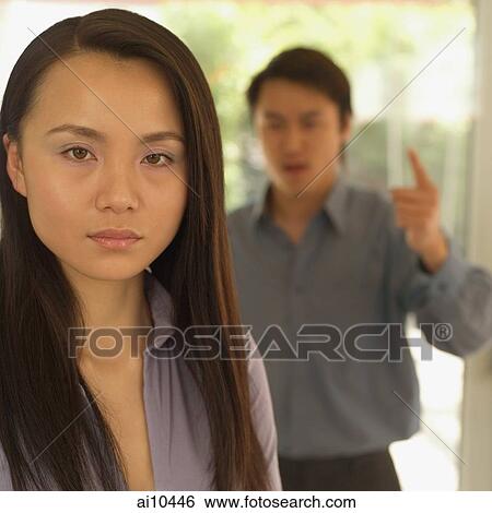 Woman looking at camera, man behind her gesturing View Large Photo Image Stock Photograph - Woman looking at camera, man behind her gesturing. Fotosearch