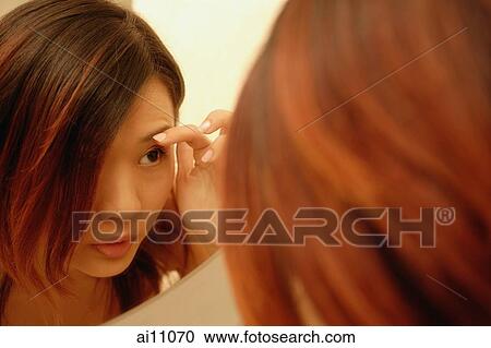 Woman looking at mirror, touching her eyebrows View Large Photo Image Stock Image - Woman looking at mirror, touching her eyebrows. Fotosearch