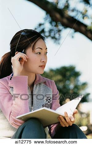 Woman looking away, holding book View Large Photo Image Stock Photography - Woman looking away, holding book. Fotosearch