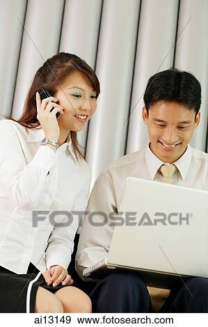 Woman on mobile phone, man next to her using laptop View Large Photo Image Stock Photo - Woman on mobile phone, man next to her using laptop. Fotosearch