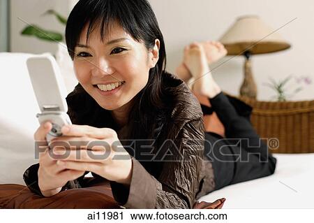 Woman on sofa, using mobile phone View Large Photo Image Stock Image - Woman on sofa, using mobile phone. Fotosearch