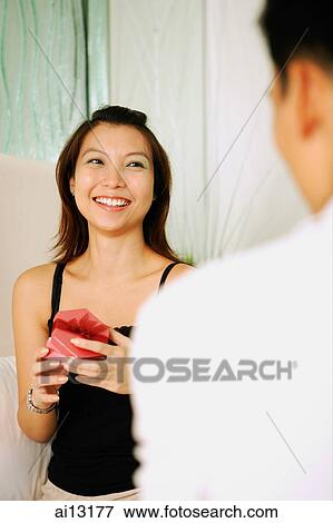 Woman opening gift box, man standing in front of her View Large Photo Image Stock Photo - Woman opening gift box, man standing in front of her. Fotosearch