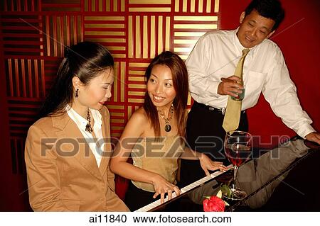 Stock Image - Woman playing the piano, friends around her. Fotosearch