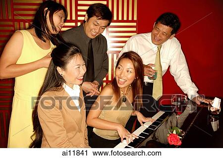 Woman playing the piano, friends around her View Large Photo Image Stock Image - Woman playing the piano, friends around her. Fotosearch
