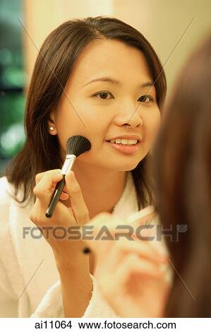 Woman putting on make-up with a blush brush View Large Photo Image Picture - Woman putting on make-up with a blush brush. Fotosearch