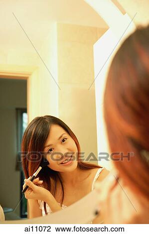 Woman putting on mascara, looking at mirror, smiling View Large Photo Image Stock Image - Woman putting on mascara, looking at mirror, smiling. Fotosearch