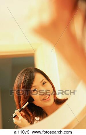Woman putting on mascara, looking at mirror, smiling View Large Photo Image Stock Image - Woman putting on mascara, looking at mirror, smiling. Fotosearch