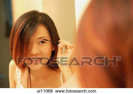 Woman putting on mascara, looking at mirror View Large Photo Image Stock Photo - Woman putting on mascara, looking at mirror. Fotosearch