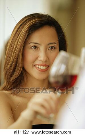 Stock Photo - Woman raising wine glass, toasting. Fotosearch