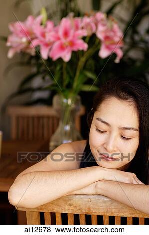 Stock Photo - Woman resting head on arms, looking down. Fotosearch