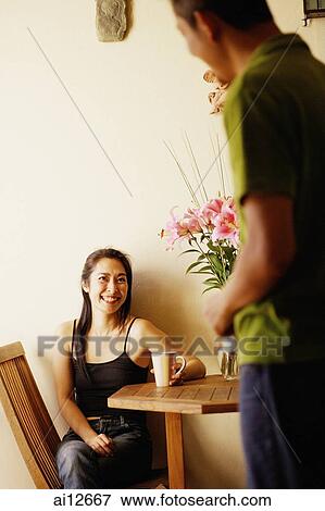 Stock Photo - Woman sitting down, man standing in front of her. Fotosearch