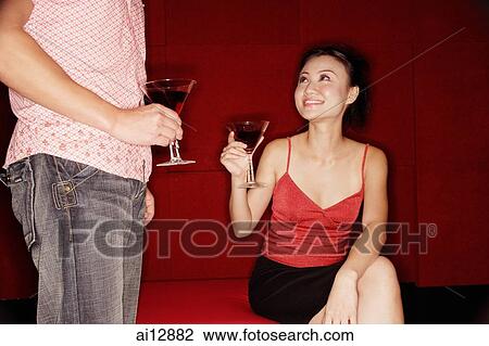 Woman sitting looking up at man, both holding drinks View Large Photo Image Stock Image - Woman sitting looking up at man, both holding drinks. Fotosearch