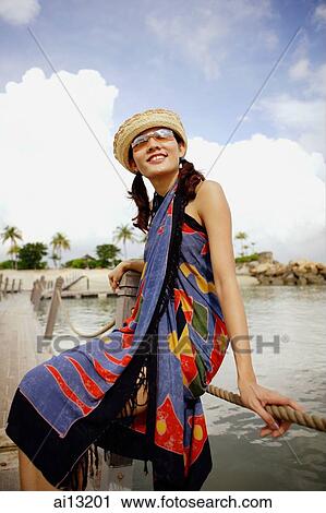 Woman sitting on jetty, looking away, smiling View Large Photo Image Stock Image - Woman sitting on jetty, looking away, smiling. Fotosearch