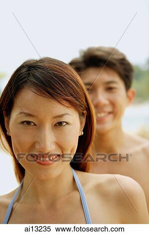 Woman smiling at camera, man in the background View Large Photo Image Stock Photography - Woman smiling at camera, man in the background. Fotosearch