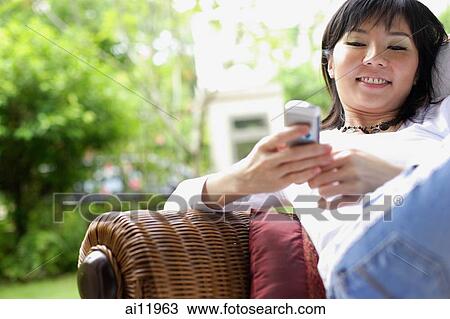 Woman using mobile phone, text messaging, smiling View Large Photo Image Stock Image - Woman using mobile phone, text messaging, smiling. Fotosearch