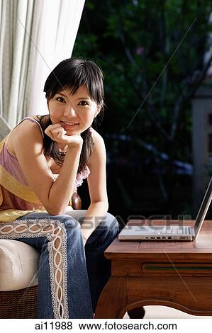 Woman with laptop, looking at camera, hand on chin View Large Photo Image Stock Photo - Woman with laptop, looking at camera, hand on chin. Fotosearch