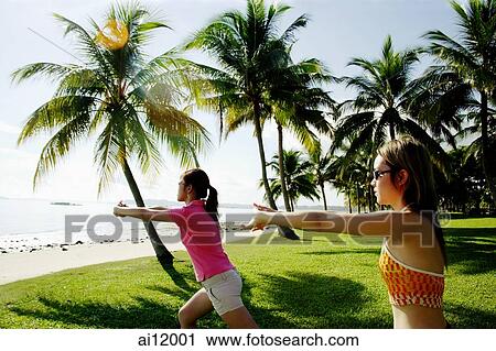 Stock Image - Women doing stretching exercises in park, arms outstretched. Fotosearch