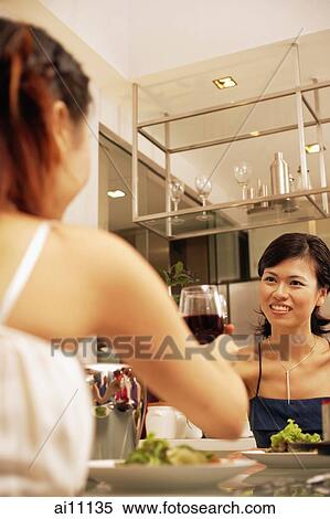Women sitting across table, raising wine glass, toasting View Large Photo Image Stock Photography - Women sitting across table, raising wine glass, toasting. Fotosearch