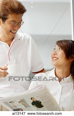 Stock Photo - Young adult with newspaper, older man with cup looking at her. Fotosearch