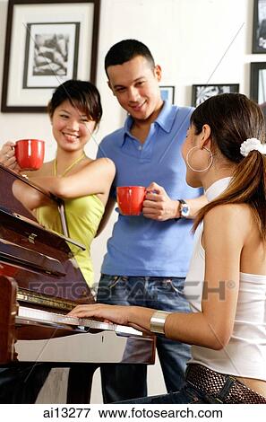 Young adults around a piano, young woman playing the piano View Large Photo Image Stock Photo - Young adults around a piano, young woman playing the piano. Fotosearch