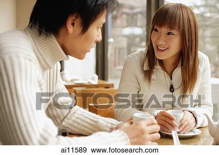 Stock Photo - Young adults at a cafe, talking, side by side. Fotosearch