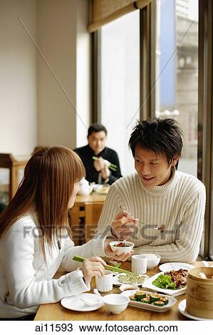 Young adults at a restaurant, eating View Large Photo Image Stock Image - Young adults at a restaurant, eating. Fotosearch
