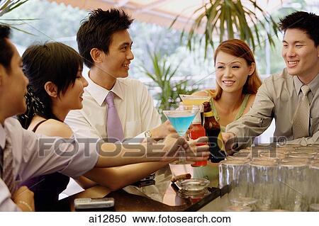 Young adults at bar counter toasting with drinks View Large Photo Image Stock Image - Young adults at bar counter toasting with drinks. Fotosearch
