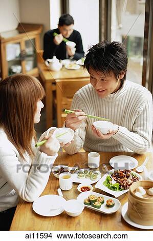 Picture - Young adults eating at a restaurant. Fotosearch