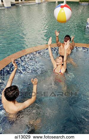 Stock Photo - Young adults in swimming pool playing with inflatable ball. Fotosearch