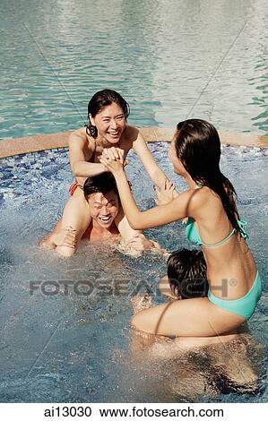 Stock Image - Young adults in swimming pool, wrestling. Fotosearch