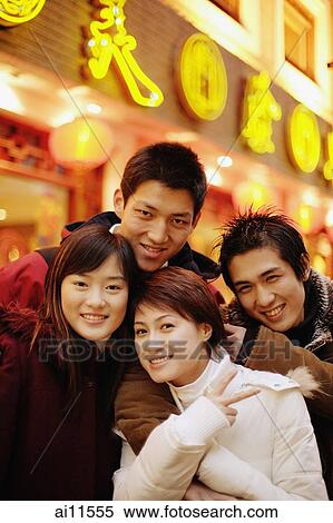 Young adults looking at camera, smiling, young woman making peace sign View Large Photo Image Stock Photography - Young adults looking at camera, smiling, young woman making peace sign. Fotosearch