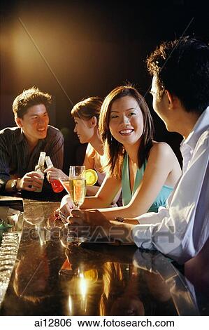 Young adults sitting at bar, talking View Large Photo Image Stock Photograph - Young adults sitting at bar, talking. Fotosearch