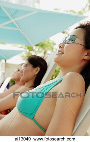 Stock Image - Young adults sunbathing, low angle view. Fotosearch