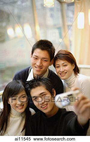 Stock Photography - Young adults taking photograph of themselves. Fotosearch