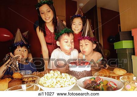 Stock Photo - Young boy blowing out candles at a birthday party.. Fotosearch