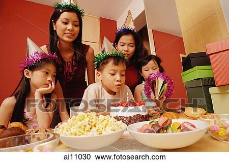 Young boy blowing out candles on a cake, surrounded by friends View Large Photo Image Stock Image - Young boy blowing out candles on a cake, surrounded by friends. Fotosearch