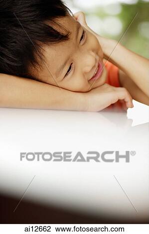 Stock Image - Young boy, head on arm. Fotosearch