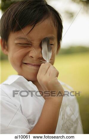 Young boy holding up feather to his face View Large Photo Image Stock Image - Young boy holding up feather to his face. Fotosearch