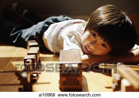 Young boy lying down with head in arms, looking at camera View Large Photo Image Stock Photo - Young boy lying down with head in arms, looking at camera. Fotosearch