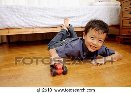 Young boy lying on floor with toy car, looking at camera View Large Photo Image Stock Image - Young boy lying on floor with toy car, looking at camera. Fotosearch
