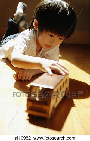 Young boy playing with toy bus, lying on front View Large Photo Image Stock Image - Young boy playing with toy bus, lying on front. Fotosearch