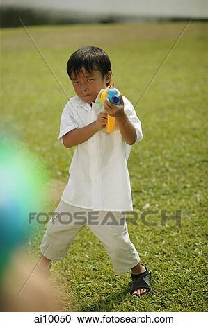 Young boy playing with water gun View Large Photo Image Stock Image - Young boy playing with water gun. Fotosearch