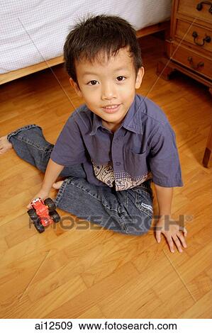Young boy sitting on floor with toy, looking at camera View Large Photo Image Stock Photo - Young boy sitting on floor with toy, looking at camera. Fotosearch